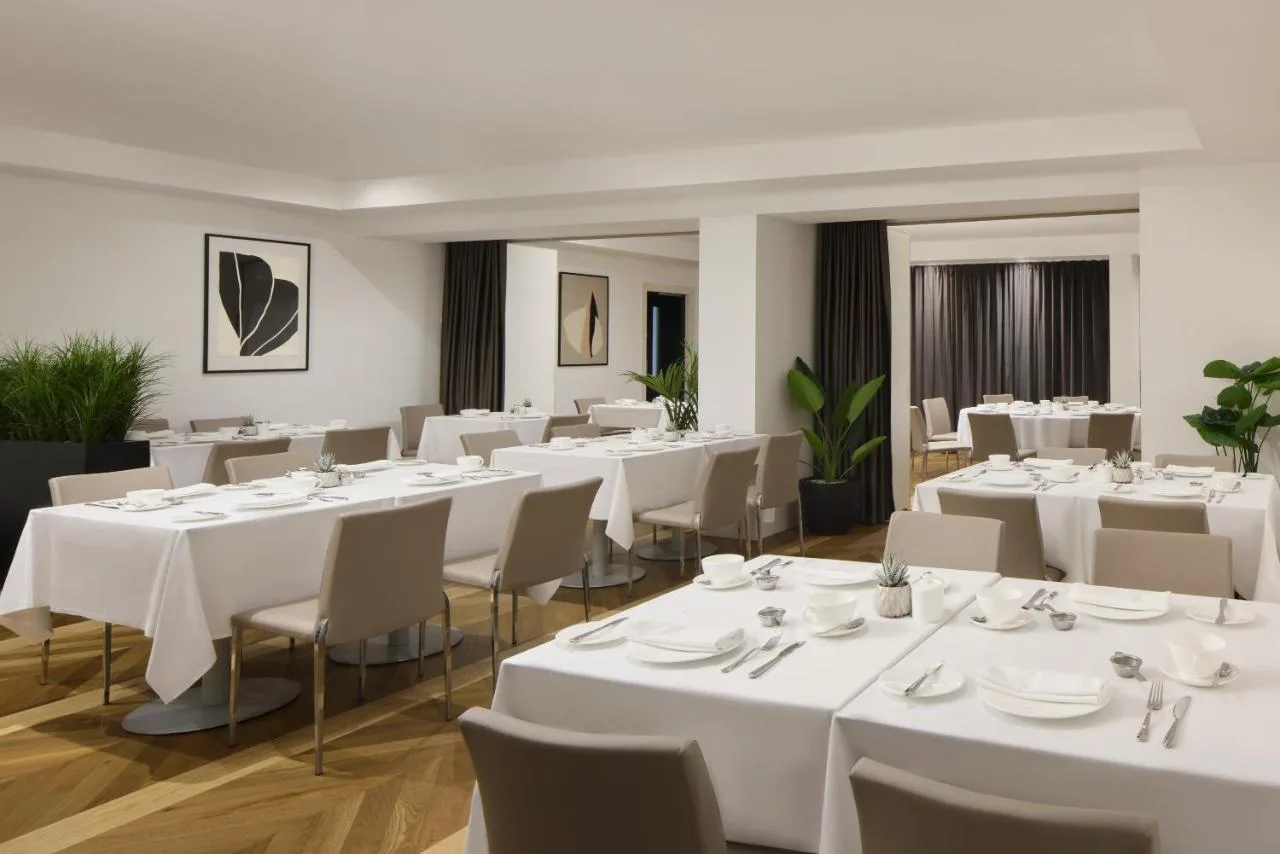 a dining room with white tables and chairs at The Queens Gate Hotel in London