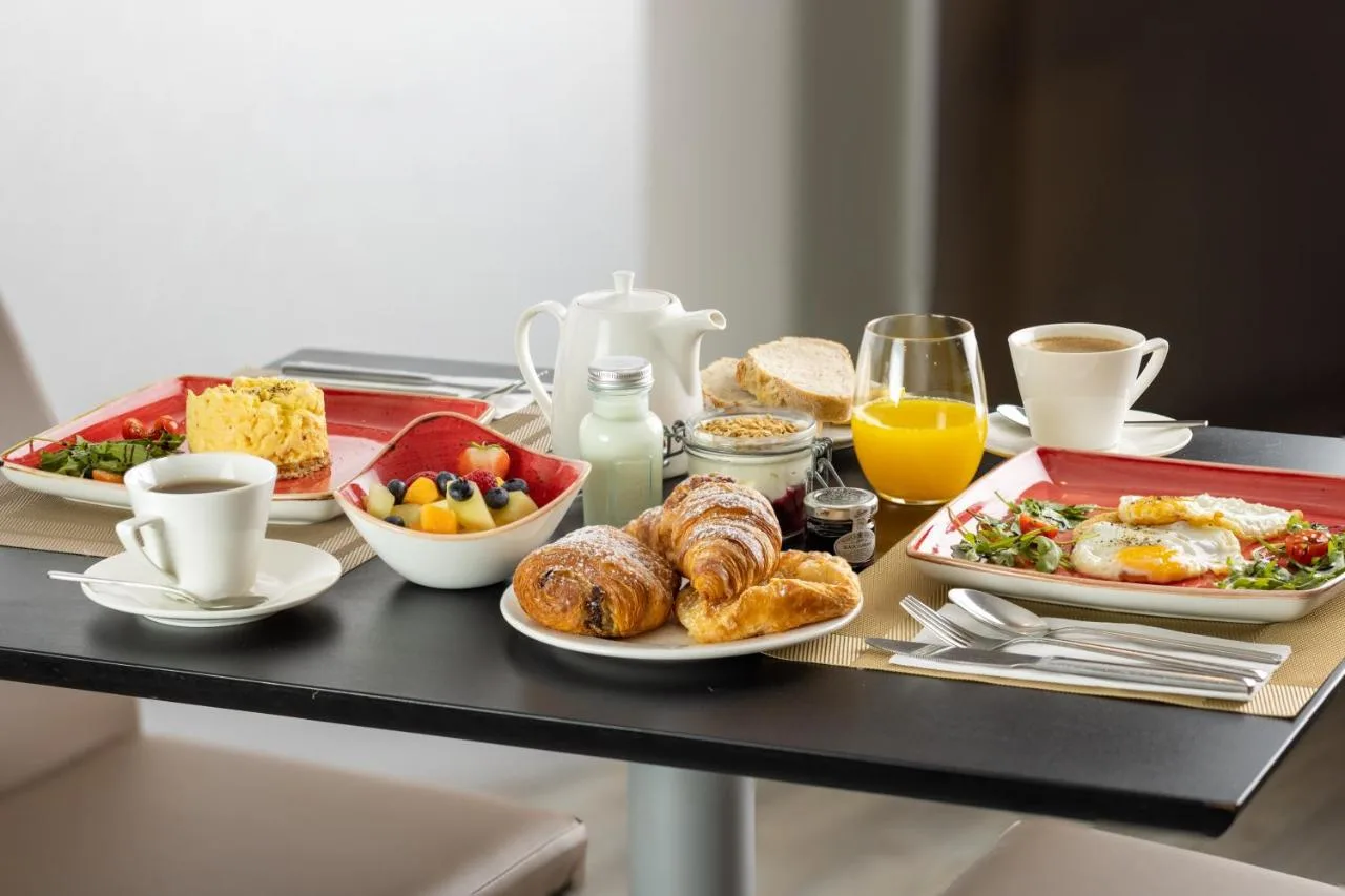a breakfast table with a tray of breakfast foods and drinks at The Queens Gate Hotel in London